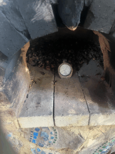 Roasting in the earth oven (I have an old school temperature gauge to know the general temp). I put a door on this in between checking!